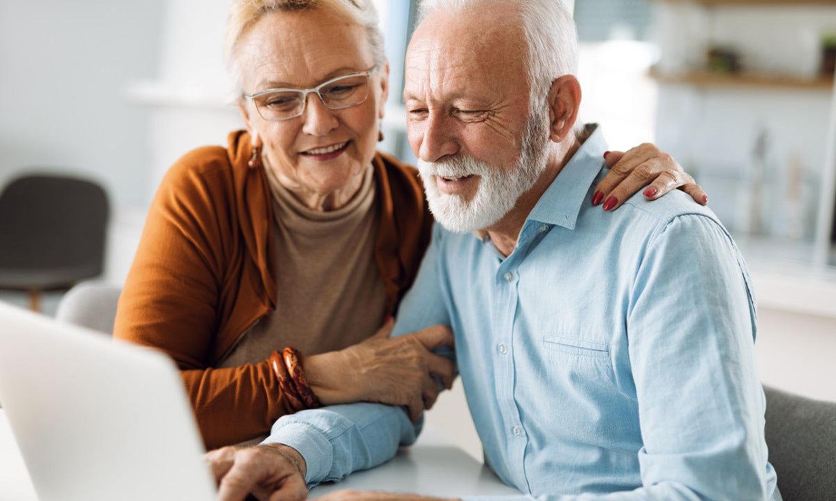 Happy senior couple using a laptop at home
